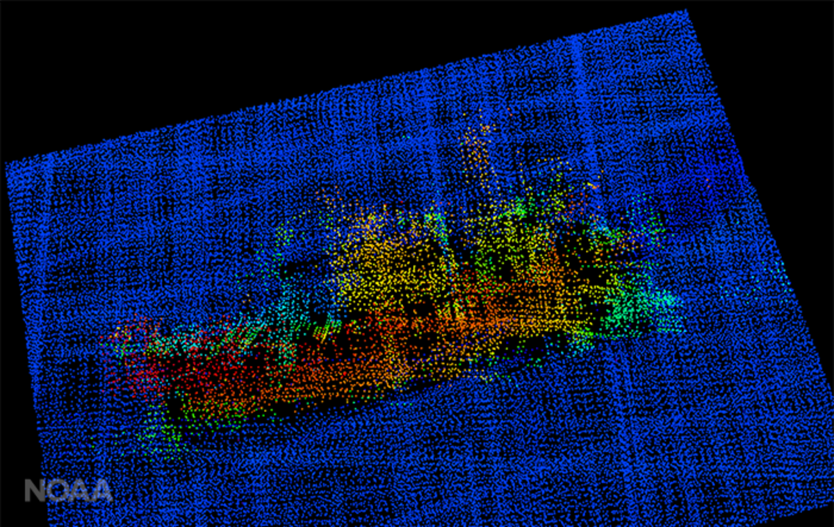 A 3-D image from NOAA Ship Fairweather multi-beam sonar. The profile of the F/V Destination is clearly visible, including the bulbous bow to the right, the forward house and mast, equipment (likely crab pots) stacked amidships, the deck crane aft, and the skeg and rudder.