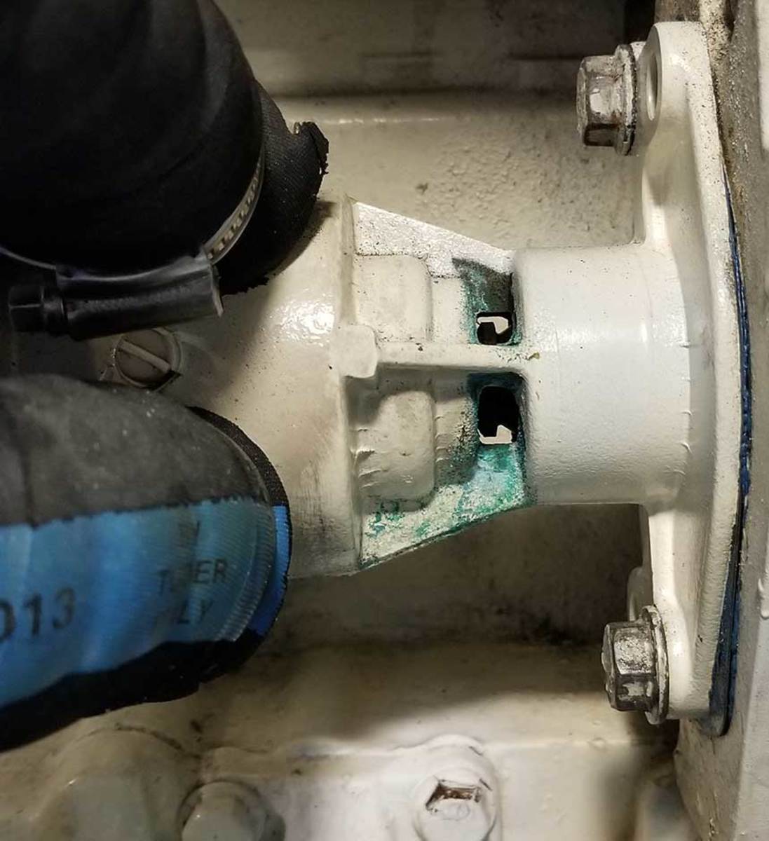 The engine seawater pump has openings that will reveal oil or seawater leaks through failing seals. The green verdigris in this image suggests a leaking seal on the seawater side. 