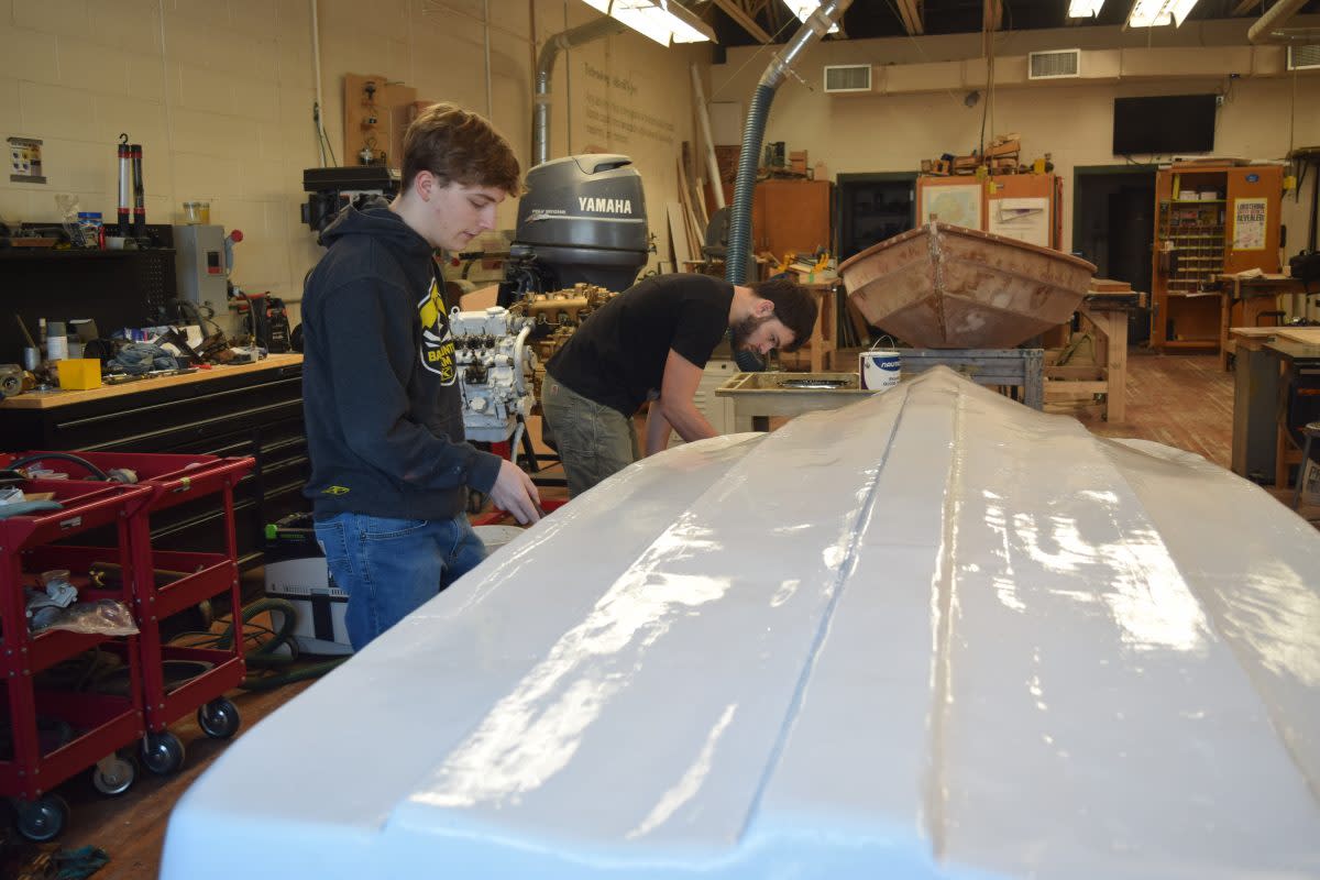 Mount Desert Island High School students Josh Willard (left) and Ivan Andros work on repairing a boat Andros found on the side of the road. Ellsworth American photo by Becky Pritchard.