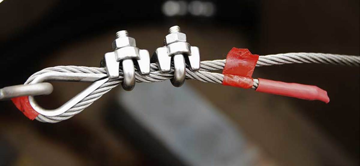 The ”dead end” of the cable has been marked with red tape. The wire clamps consist of a U-bolt and a saddle. These clamps have been installed properly, with the U-bolts on the dead end of the cable and the saddles on the working or standing side of the cable. 
