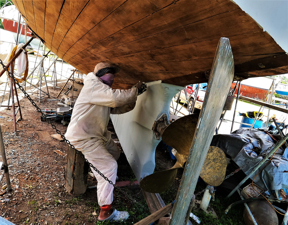 Removing old caulking from her original hull planking in preparation for a complete bottom job.