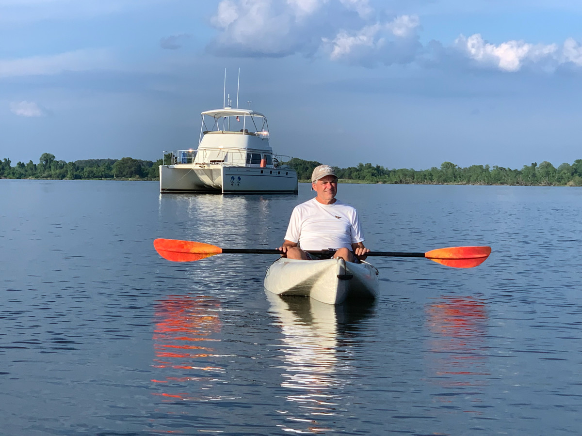 Most catamarans are shoal draft, which permits anchoring closer to shore, away from many other boats and closer to beaches or other  attractions. Pictured here, Jim enjoys a kayak excursion in front of an anchored Thing 1 Thing 2 at Easton, Maryland, in the Chesapeake Bay.