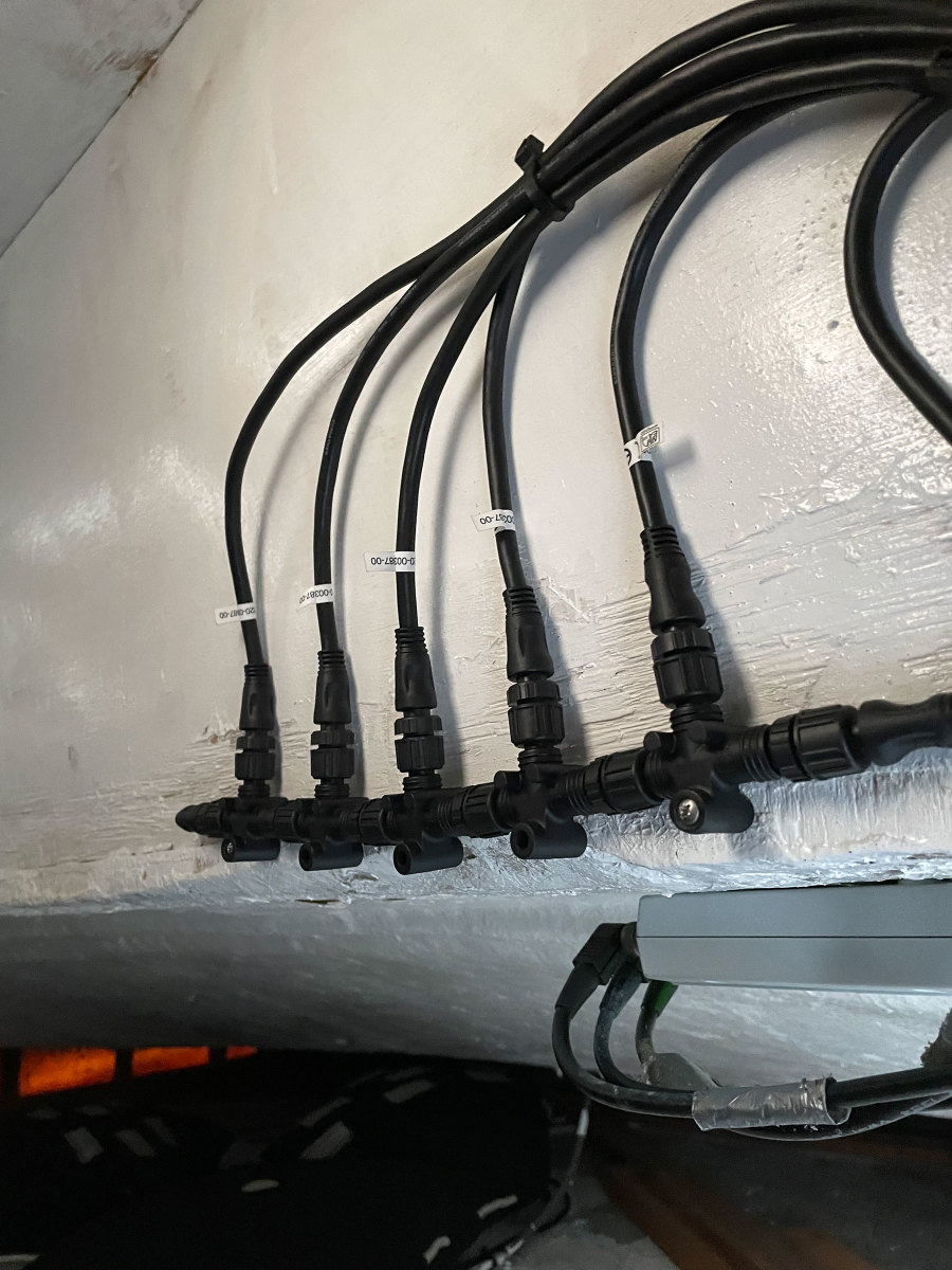 This portion of an NMEA 2000 backbone shows the Ts and cable drops heading off to carry data to and from individual devices. On the far left, note the pointed terminator installed in the last T. 