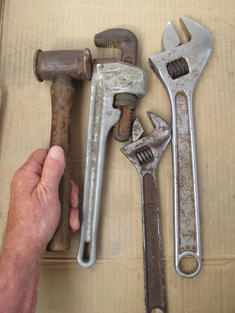 Some of the author's tools came with him to the States from the U.K. over 50 years ago, and continue to provide excellent service. The author uses a pipe wrench to undo a threaded collar holding a bearing in place, then heats the bearing to expand it, so it can be removed from the shaft. Like his other trusty hand tools, the vice grips show their age but still perform. Boaters should have small and medium-sized vice grips in their kits, with both straight- and curved-jaw models.