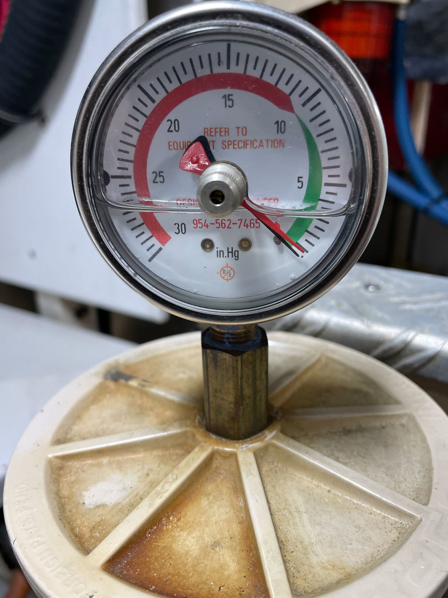 Mechanical vacuum gauges can replace the T-handle on the tops of some primary filters, making for an easy way to monitor filter condition. The black needle shows the vacuum. The red needle is a resettable telltale that will record the highest vacuum the gauge sees. 